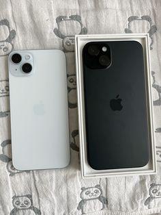 two iphones are sitting next to each other in a box on a bed with a white and black cover