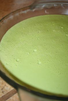 a glass bowl filled with green liquid on top of a counter