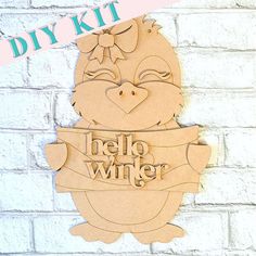 Adorn your home with the Penguin Girl Door Hanger from Janet's Craft Corner. This delightful DIY kit includes a wooden cutout of a cartoon penguin girl carrying a banner that reads hello winter. Featuring a charming bow on her head, this decorative piece is perfect for winter decor and looks lovely against a white brick wall. Door Penguin, Americana Paint, Penguin Love, Winter Signs, Hello Winter, Craft Corner, Diy Craft Kits, Glue Crafts, Super Glue