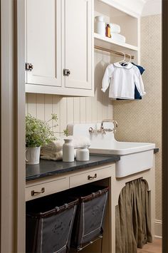 a kitchen with white cabinets and black counter tops next to an open door that leads to a laundry room