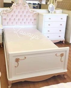 there is a white bed with pink upholstered headboard and drawers in the room