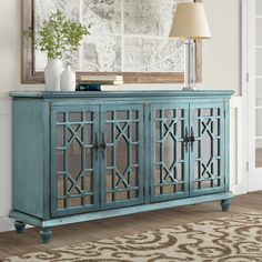 a blue sideboard with glass doors in front of a mirror and rug on the floor