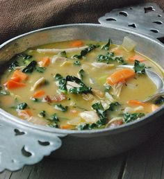 a metal bowl filled with soup on top of a wooden table