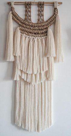 a white wall hanging with tassels on it's sides and a wooden hanger