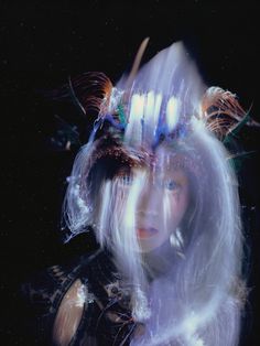 a woman with long white hair and feathers on her head is shown in the image