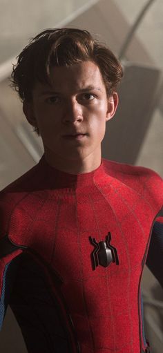 a young man in a spider - man suit looks at the camera with an apple on his chest