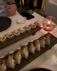 some food is laying out on a long wooden tray next to a glass of wine