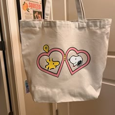 a tote bag with two hearts and a dog on it hanging from a door