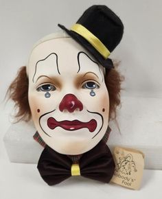 a clown mask with a top hat and bow tie on it's head next to a tag