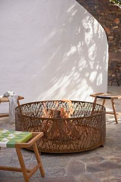 a fire pit sitting on top of a stone floor next to two chairs and a table