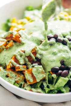 a white bowl filled with lettuce, black beans and guacamole