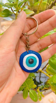 a hand holding a blue and white evil eye keychain in it's palm