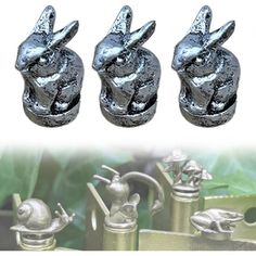 three metal rabbits on top of each other in front of green leaves and the bottom one has