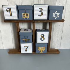 four boxes with numbers and symbols on them sitting on a wooden shelf in front of a white wall