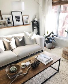 a living room with white couches and pictures on the window sill above it