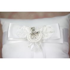 a close up of a white pillow with a flower on the front and a bow at the back