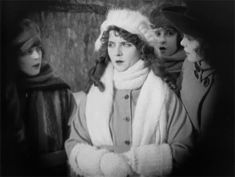 an old black and white photo of three women in winter clothing, one wearing a fur hat