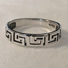 a silver ring with an interlocked design on the outside and inside, sitting on a white surface