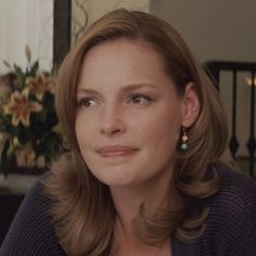 a woman with brown hair and earrings sitting in front of a window looking off into the distance