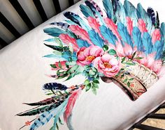 a baby crib with an image of feathers and flowers on it