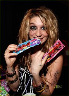 a woman with makeup on her face holding up a candy bar