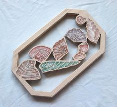 a wooden frame with seashells in it on a white tableclothed surface