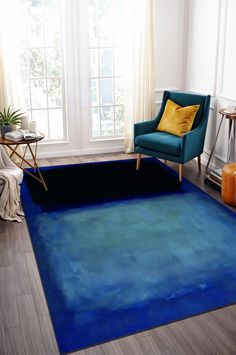 a blue area rug in a living room with a green chair and yellow throw pillow