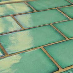 a close up view of green tiles on the floor with gold trim and grouting