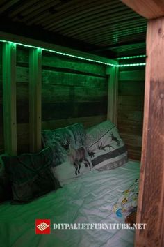 a bed in a room with green lights on the wall and pillows under it,