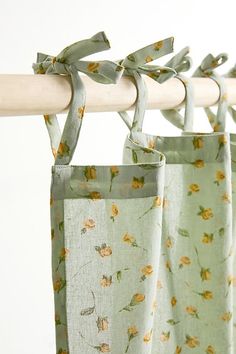 two bags hanging from a wooden rod with flowers on them and tied to the side