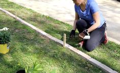 a woman kneeling down to plant flowers in the grass