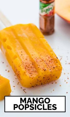 mango popsicles on a plate with seasoning next to them