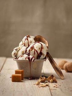 an ice cream sundae with chocolate sauce drizzled on top and nuts scattered around