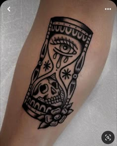 a black and white tattoo on the leg of a person with an hourglass in it