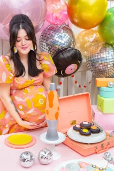 a pregnant woman sitting at a table surrounded by balloons