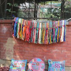 colorful pillows and blankets on the ground next to a brick wall