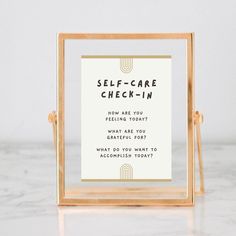 the self - care check - in sign is displayed on a marble countertop with gold frame