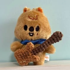 a brown teddy bear holding a crocheted guitar