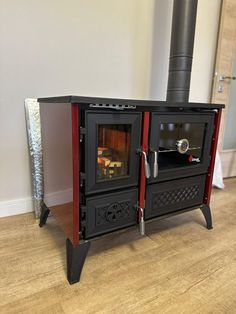 a black and red stove sitting on top of a hard wood floor