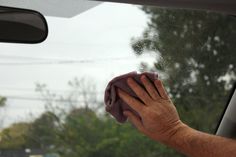 a man wiping his hands with a cloth in the back seat of a car on a rainy day