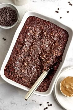 a pan filled with chocolate cake next to two bowls of peanut butter