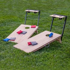 two wooden boards sitting on top of a grass covered field next to tables with red and blue cloths