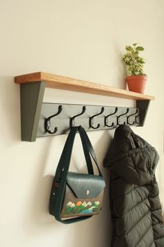 a coat rack with two coats hanging from it's sides and a purse hanging on the wall