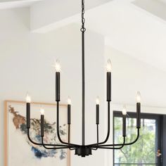 a black chandelier hanging from the ceiling in a room with white walls and windows