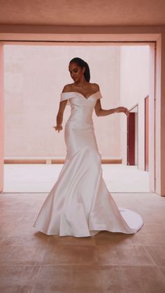 a woman in a white wedding dress is standing on the floor with her arms outstretched