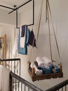 a hanging basket filled with towels on top of a stair case next to a bed