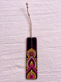 a bookmark hanging from a string on a white sheet with a beaded design