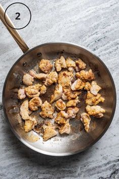 a pan filled with chicken and seasoning sitting on top of a marble countertop