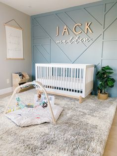 a baby's room with a white crib in the middle and a blue wall behind it