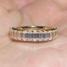 a woman's hand holding a gold ring with three baguettes